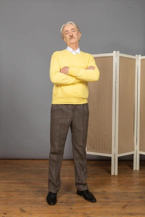 Front view of a displeased old man crossing hands