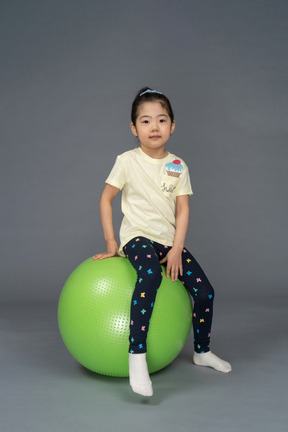 Little girl sitting on a green fitball