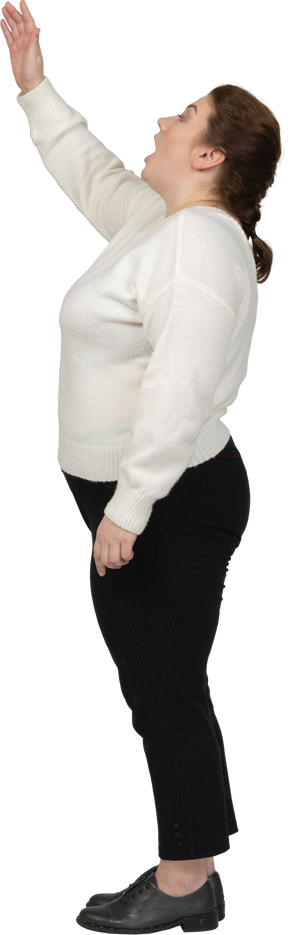 Side view of a plus size woman in casual clothes standing with raised arm