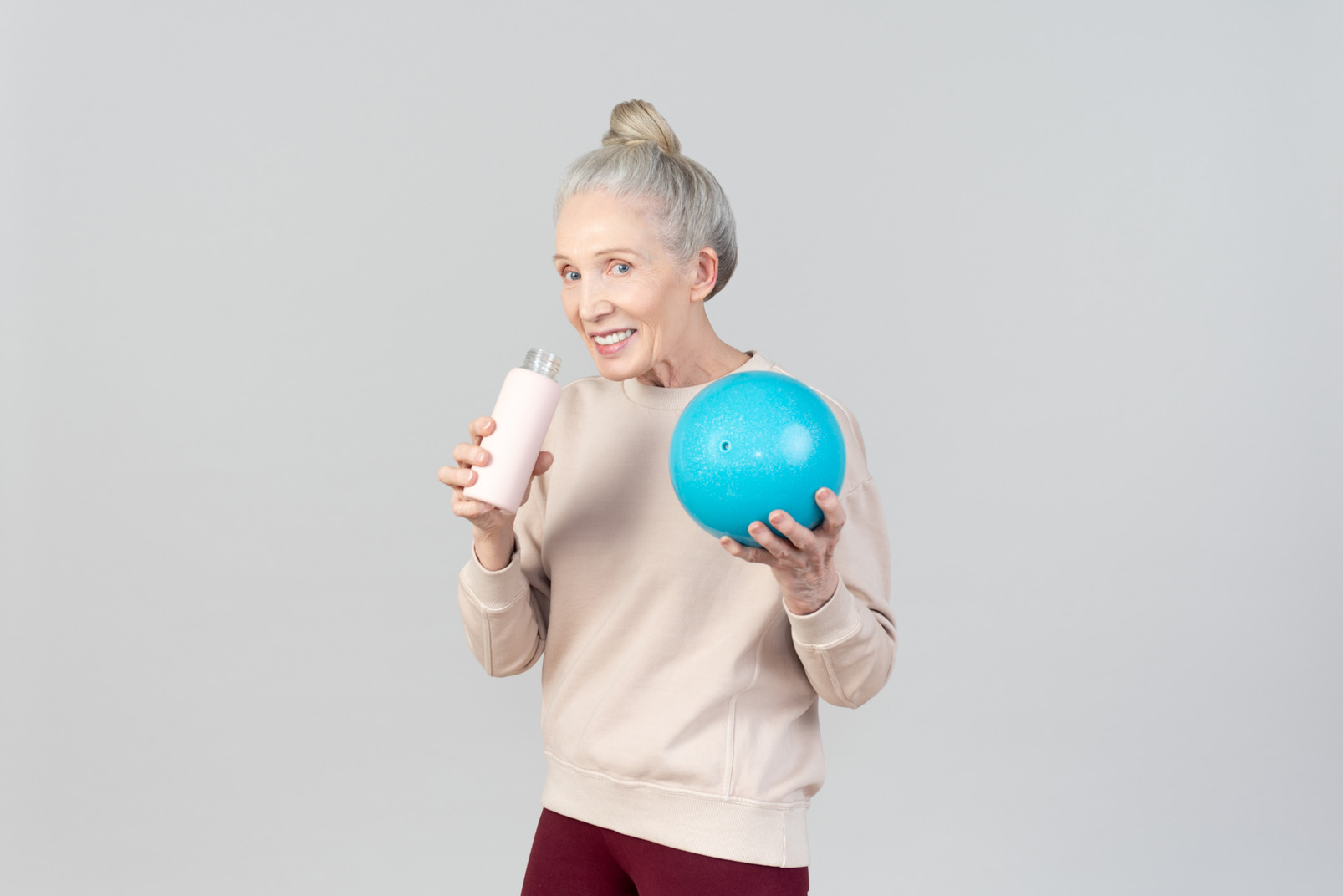 Old woman holding light blue ball and sports bottle
