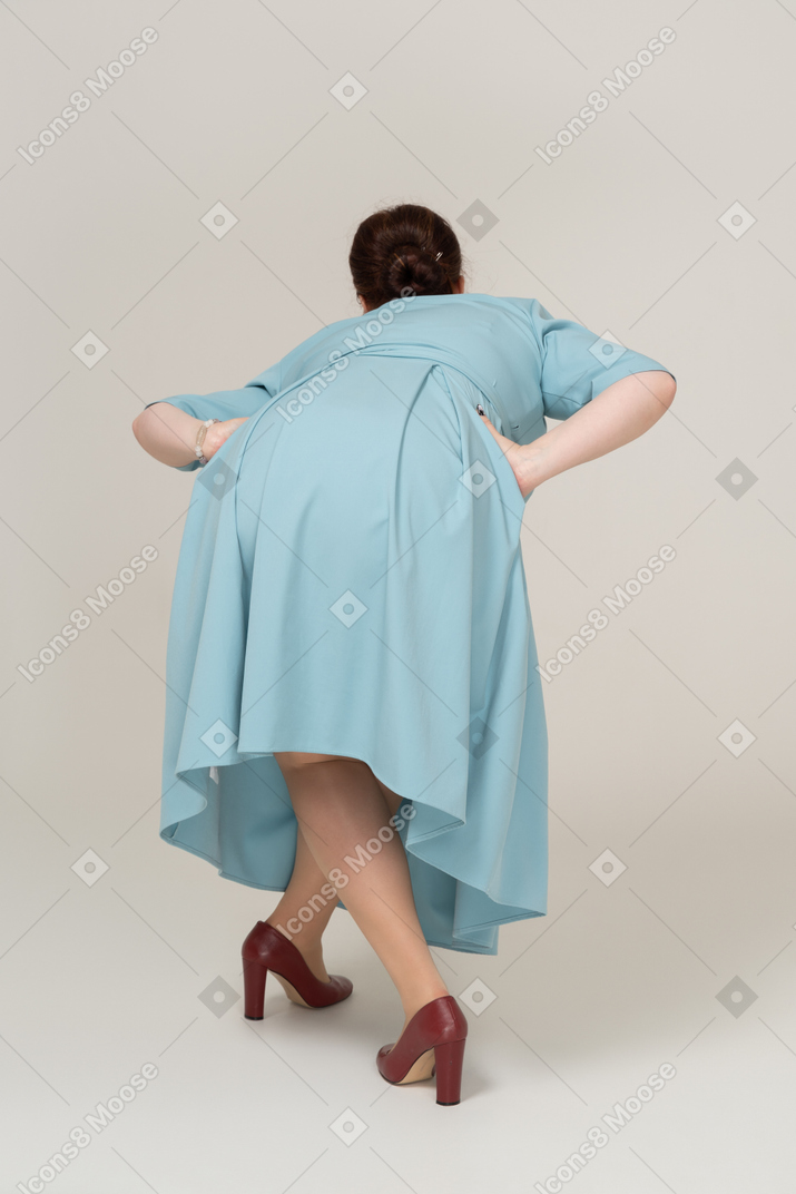 一个穿蓝色裙子的女人弯下腰的后视图