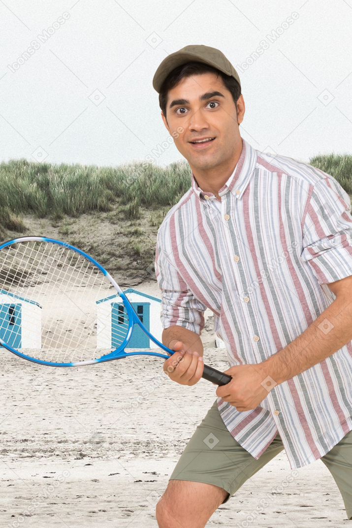 A man holding a tennis racquet on a beach