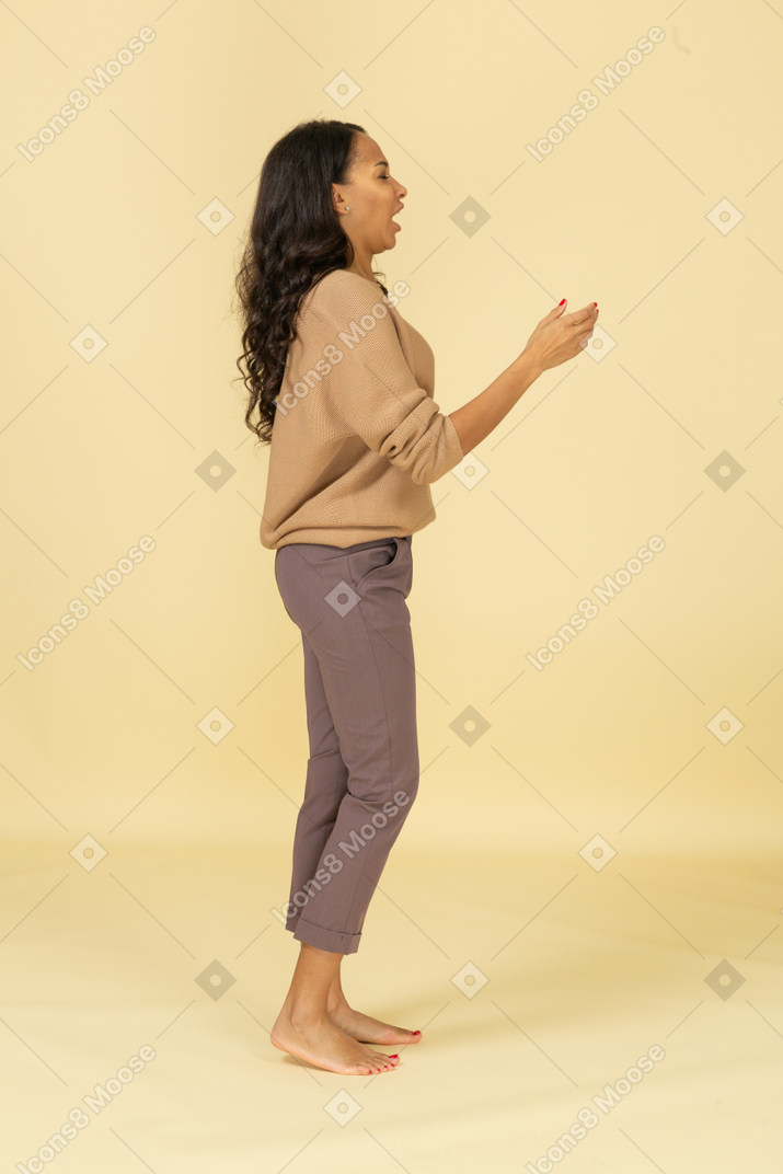 Side view of a talking young dark-skinned female raising her hand