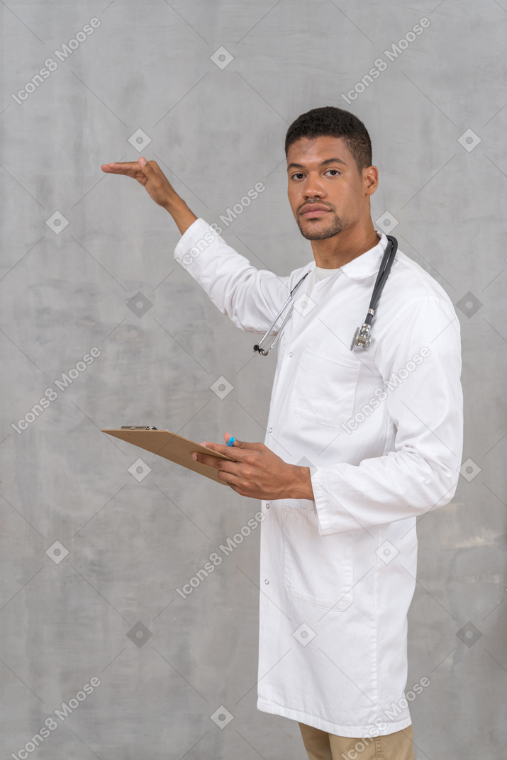 Médico varón sosteniendo un portapapeles y gesticulando