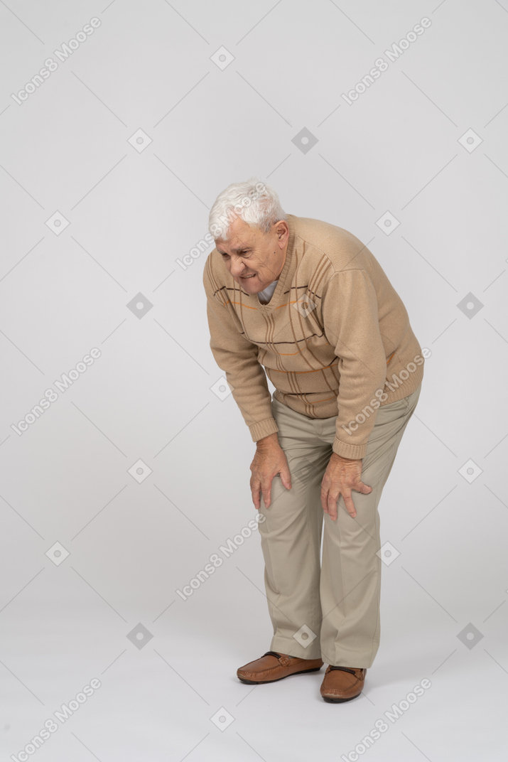 Vista frontale di un vecchio che si china e si tocca le ginocchia doloranti