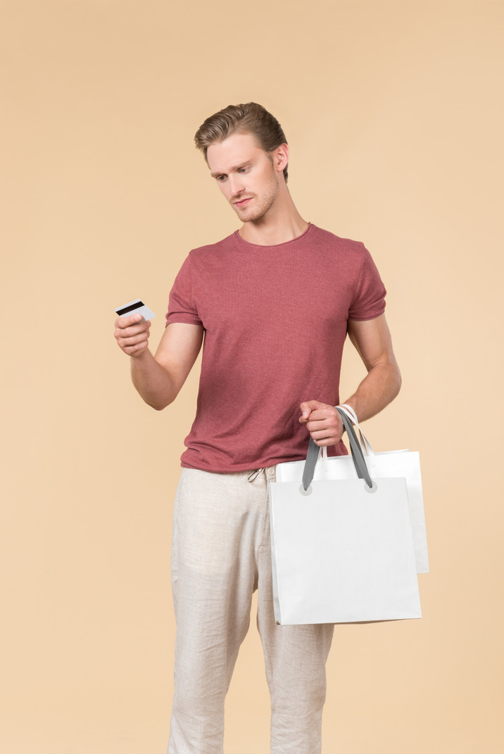 Young guy holding white shopping bags and a credit card