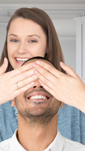 A woman covering man's eyes with her hands