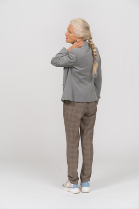 Vista trasera de una anciana en traje tocándose el cuello