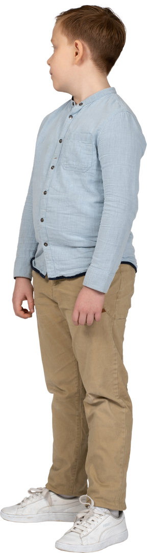 Vista lateral de un niño con ropa informal parado y mirando a un lado