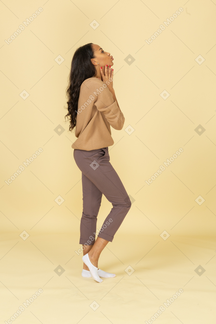 Side view of an attractive dark-skinned young lady touching her neck