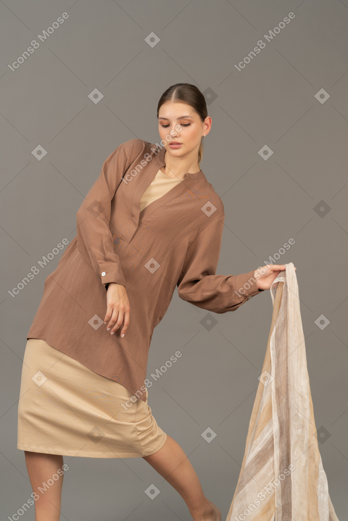 Молодая женщина в бежевой одежде позирует с шарфом