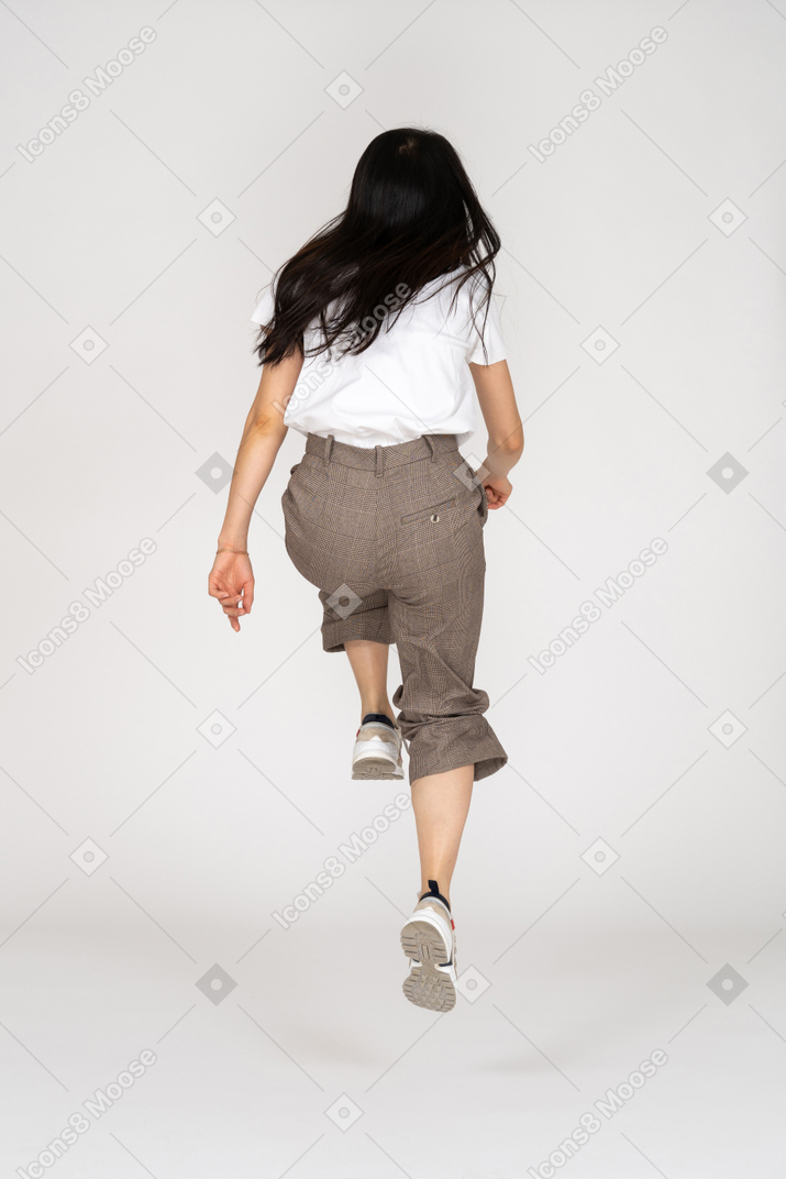 Back view of a jumping young lady in breeches and t-shirt bending knees