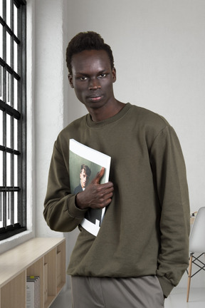 A man standing in front of a window holding a book