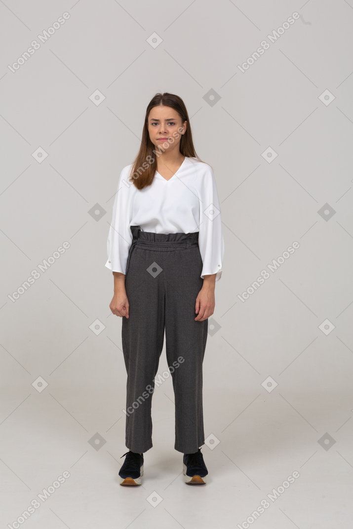 Front view of a confused young lady in office clothing looking at camera and clenching fist
