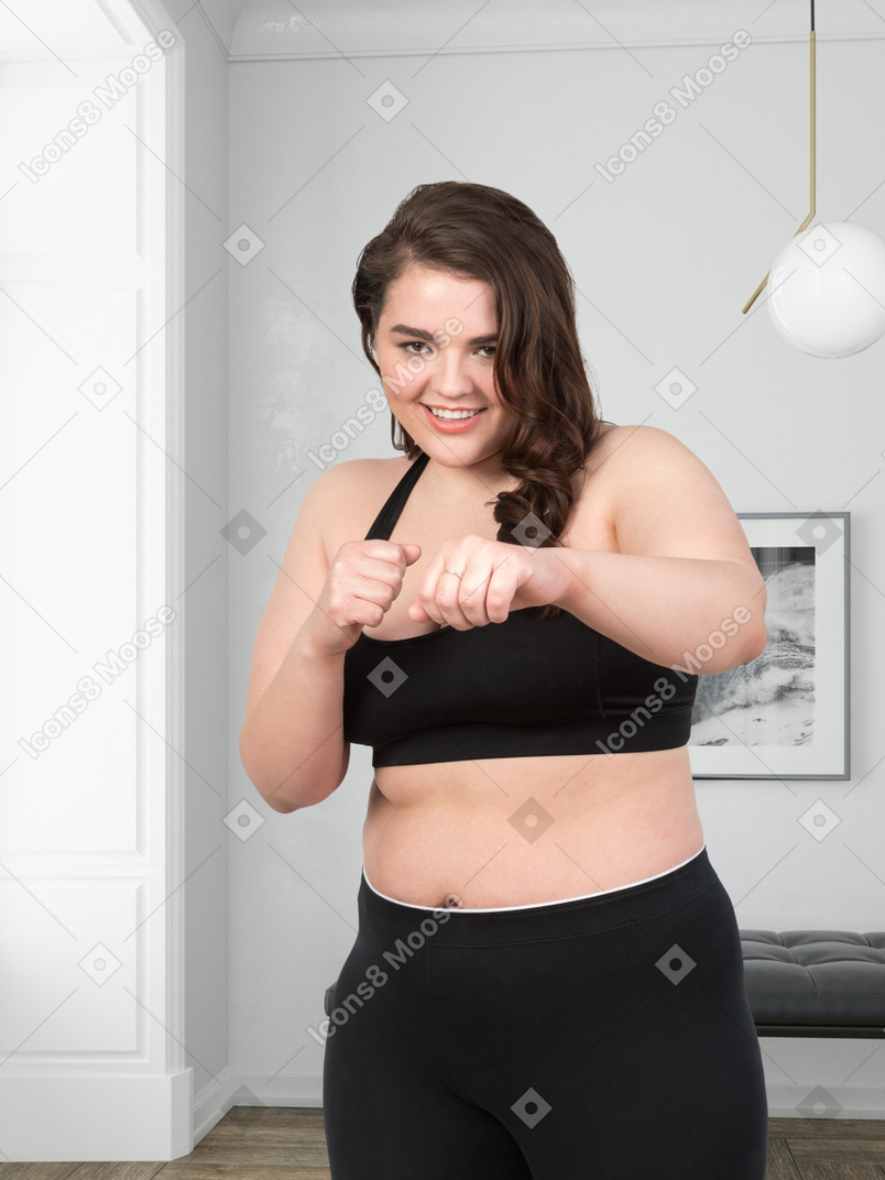 Woman in a black bra top boxing and looking at the camera