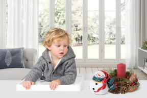 A little boy sitting next to a christmas decoration