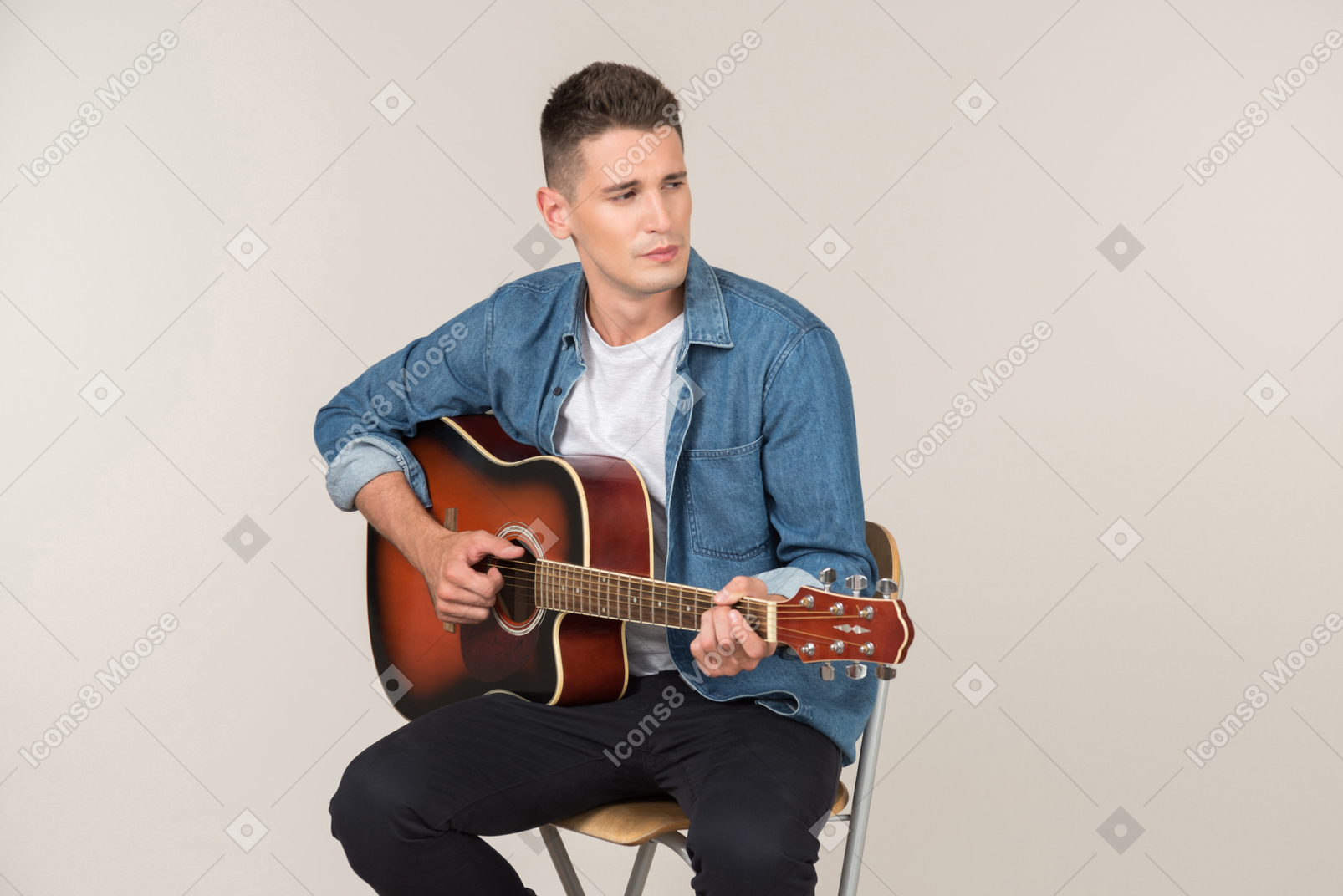 Young stand-up comic playing on guitar and looking aside