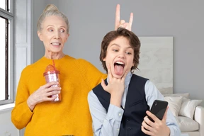 An older woman and a young boy making a rock hand gesture in a living room
