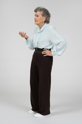 Three-quarter view of an old woman gesturing in question