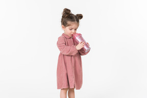 从粉红色的塑料杯喝的小小孩女孩