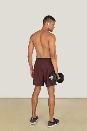 Vista traseira do homem atlético bonito vestido com shorts vermelhos e tênis preto