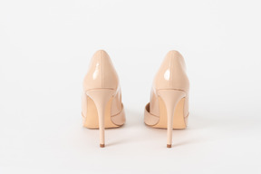 Una toma trasera de un par de zapatos de tacón de aguja lacados en beige