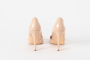 A back shot of a pair of beige lacquered stiletto shoes