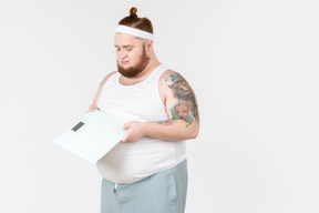 Sad big guy in sportswear holding digital weights