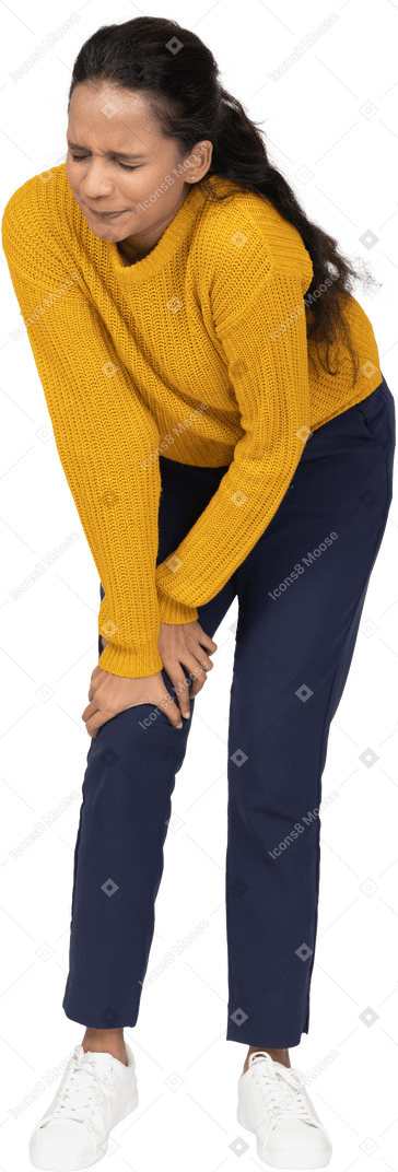 Front view of a girl in casual clothes touching hurting knee