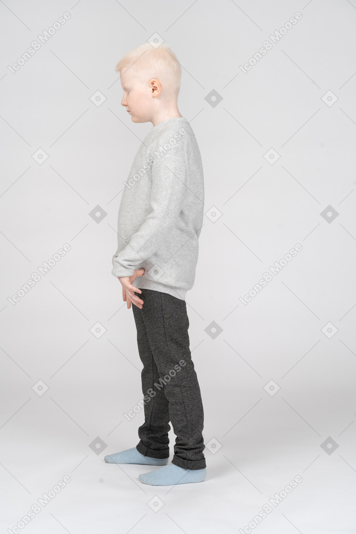 一个金发碧眼的小男孩，穿着休闲服站在一起展开手指的侧视图