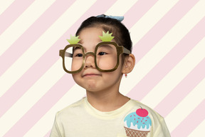 A little girl wearing large toy glasses