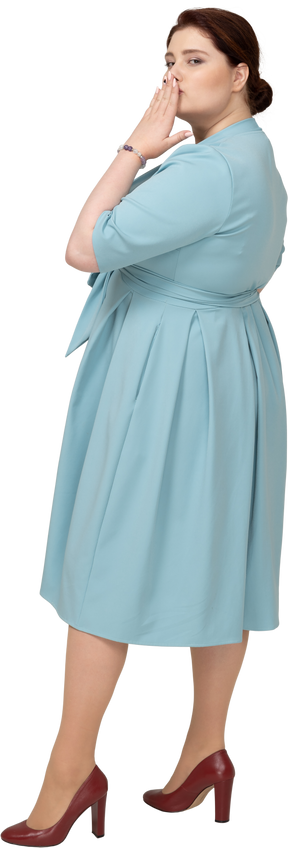 Вид сбоку на женщину в синем платье, отправляющую воздушный поцелуй