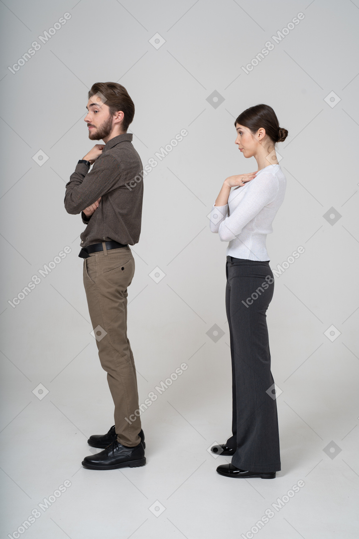 Vista laterale di una giovane coppia prepotente in abiti da ufficio toccando il petto