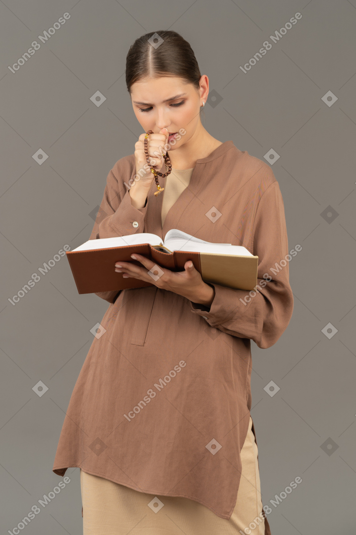 手放在嘴唇上看书的年轻女人