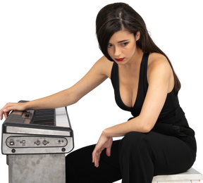 Full-length of a sad young female sitting by the piano while looking down