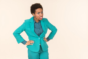 Black woman with a short haircut, wearing all blue, standing against a plain pastel background, looking emotional