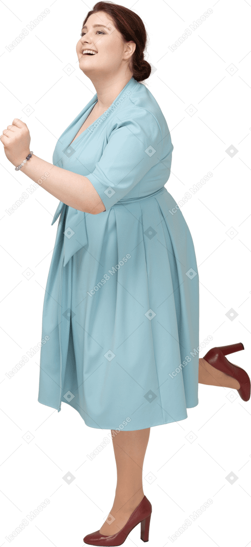 一个穿着蓝色连衣裙的女人在一条腿上保持平衡的侧视图