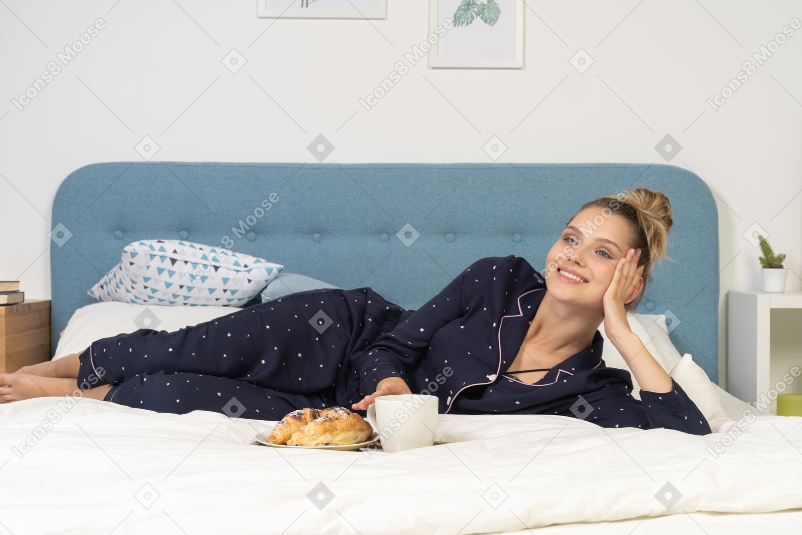 Front view of a laying in bed young lady having breakfast