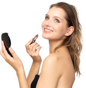 Side view of a smiling young woman applying lipstick while holding a mirror