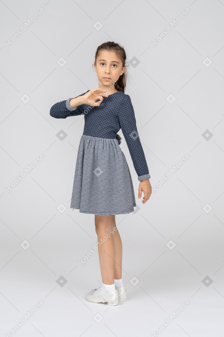 Three-quarter back view of a girl turning and making an okay sign
