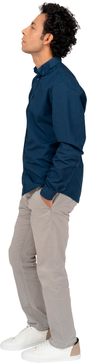 Vista lateral de um homem com roupas casuais em pé com as mãos nos bolsos