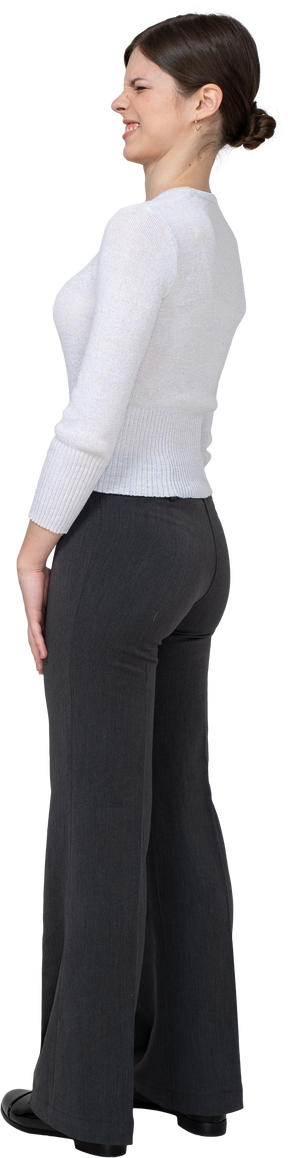 Vista posteriore di tre quarti di una giovane donna dispiaciuta con una smorfia in abiti da ufficio office