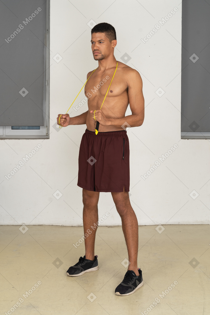 Bare chested man in sport shorts standing with jumping rope over his neck