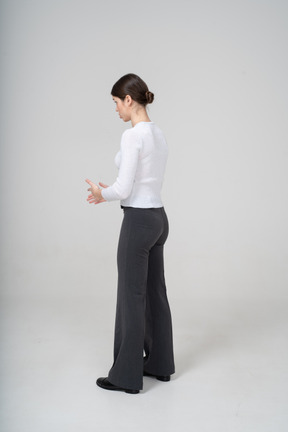 Giovane donna in pantaloni neri e camicetta bianca in piedi di profilo