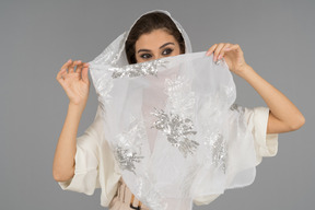 Allegra giovane donna araba che copre il viso con scialle bianco con ricami d'argento