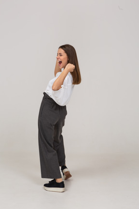 Side view of a happy young lady in office clothing raising hands