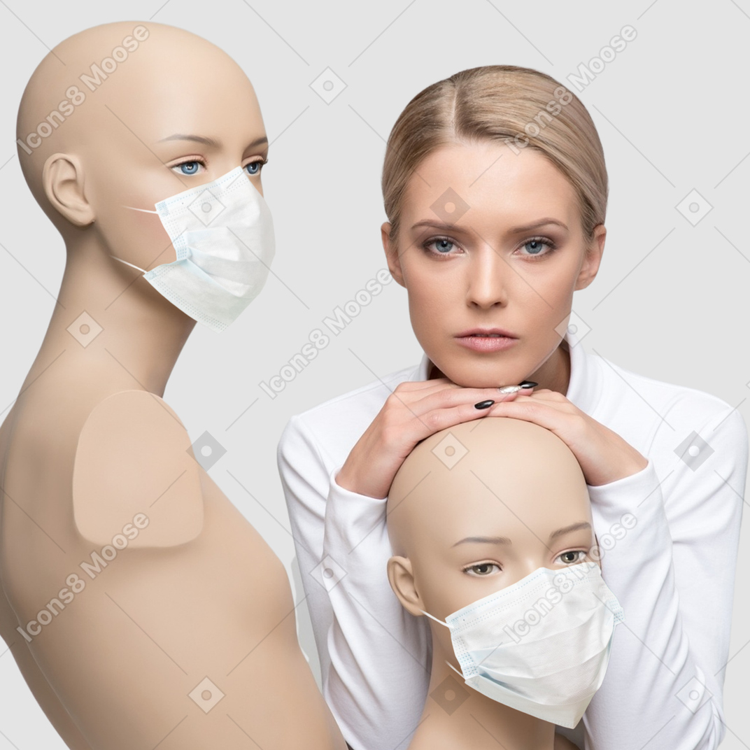 A woman standing next to a couple of mannequins in face masks 