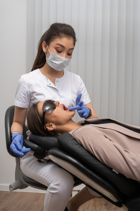 Una dentista en máscara examinando a su paciente con gafas médicas