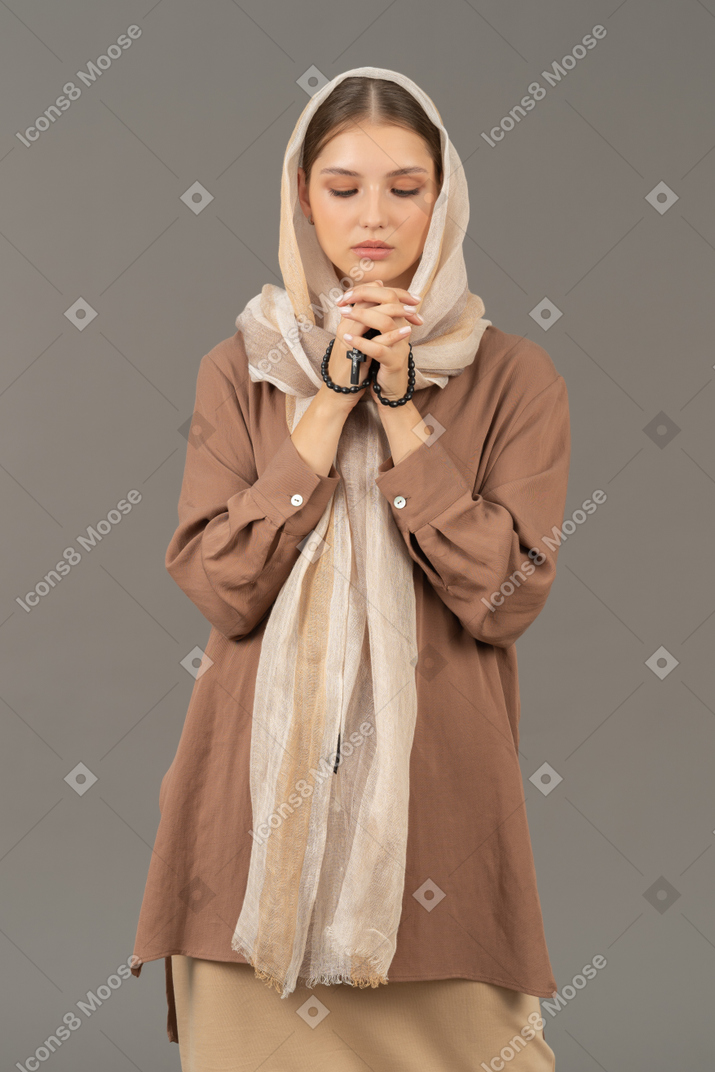 Mujer joven rezando con cuentas de rosario