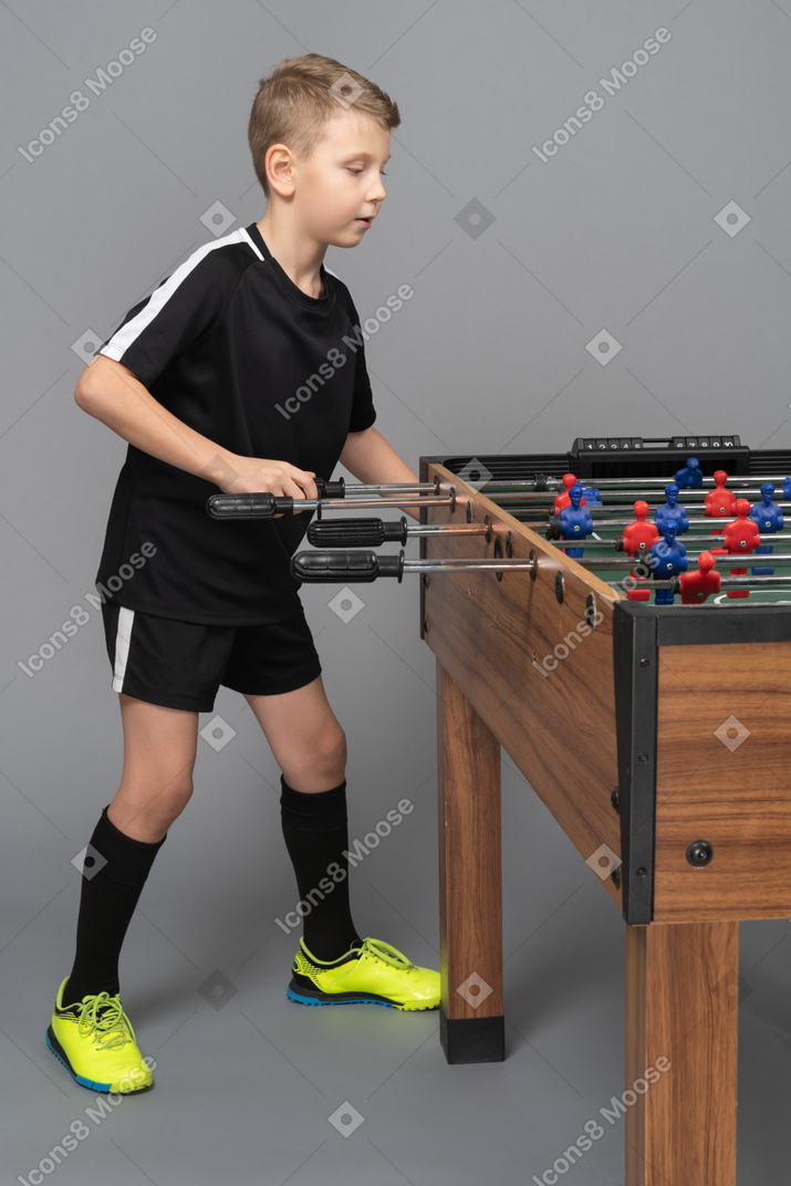 一个男孩玩桌上足球的侧视图